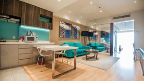 A modern kitchen with a dining area, a teal sofa, and a large mirror. - D'Majestic Place by Widebed (Kuala Lumpur)