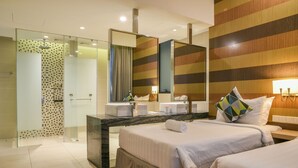 A hotel room with a glass-enclosed shower, a marble vanity, a large mirror, and two beds with white linens and decorative pillows. - D'Majestic Place by Widebed (Kuala Lumpur)