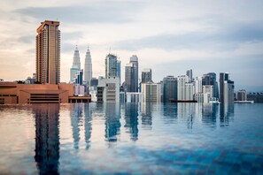 A city skyline reflected in a body of water with high-rise buildings, including a prominent tower. - D'Majestic Place by Widebed (Kuala Lumpur)