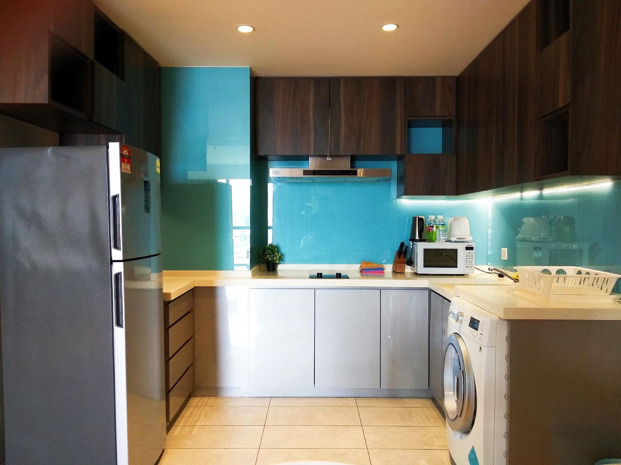 A modern kitchen with a built-in washing machine, a microwave, and a sink.