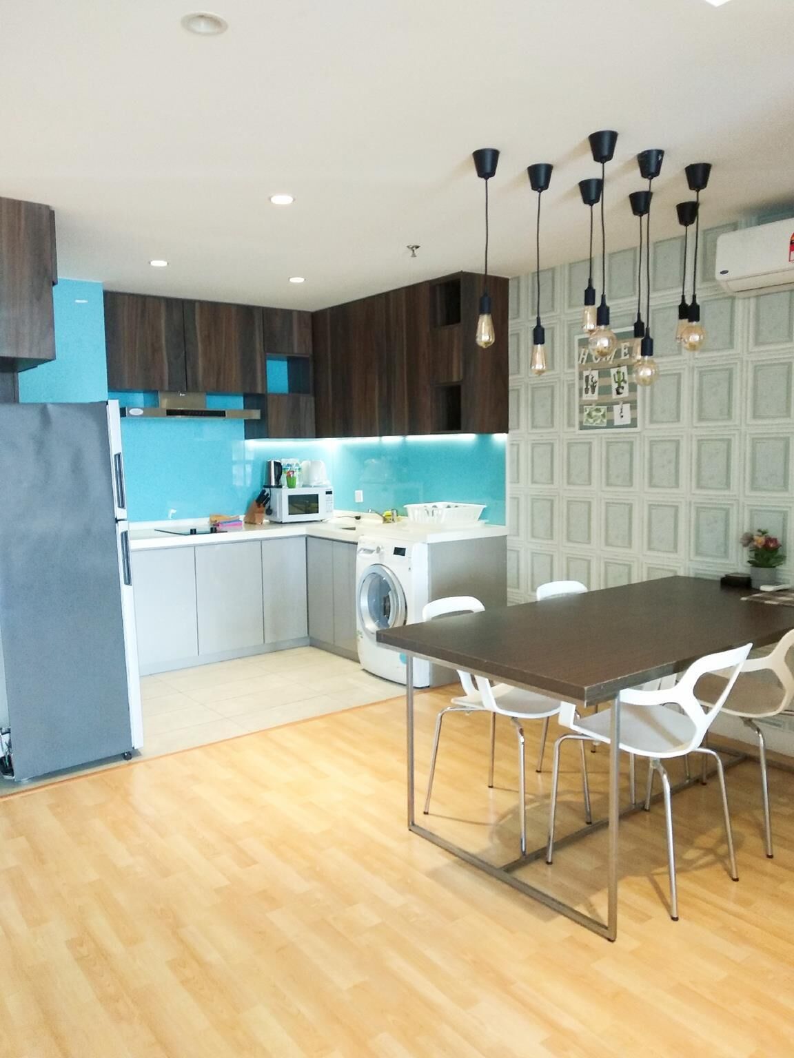 Een moderne keuken met een centraal eiland, inbouwapparatuur en hanglampen.