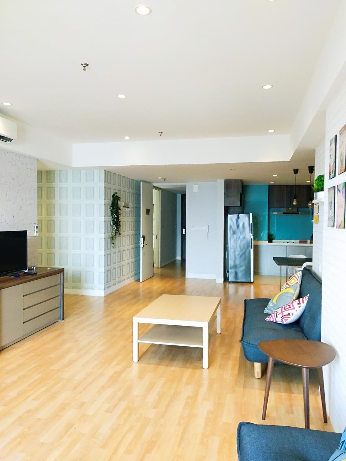 Een moderne woonkamer met houten vloer, een bank, een salontafel en een televisie op een kast.