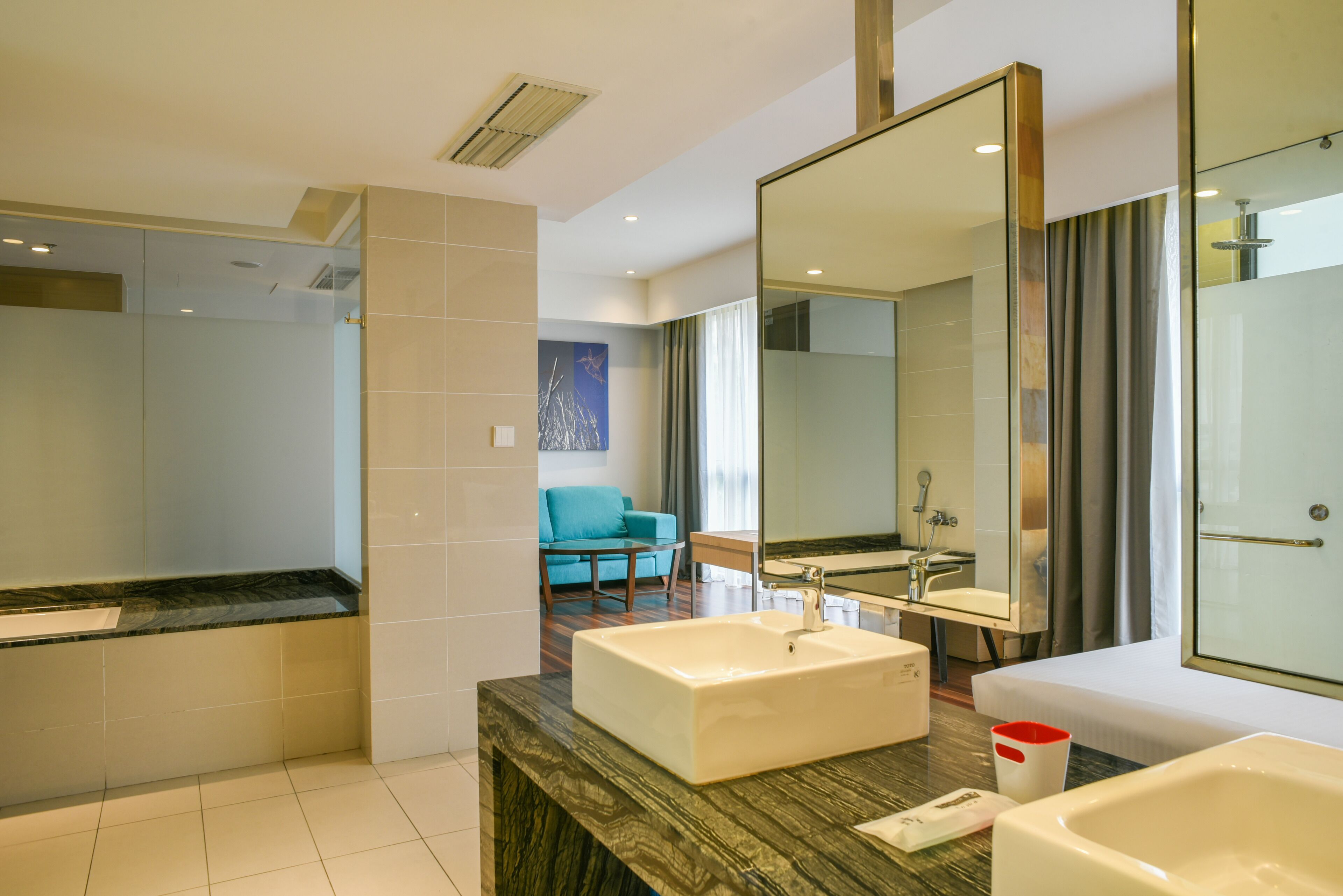 A modern bathroom with a large mirror, two sinks, and a shower area.