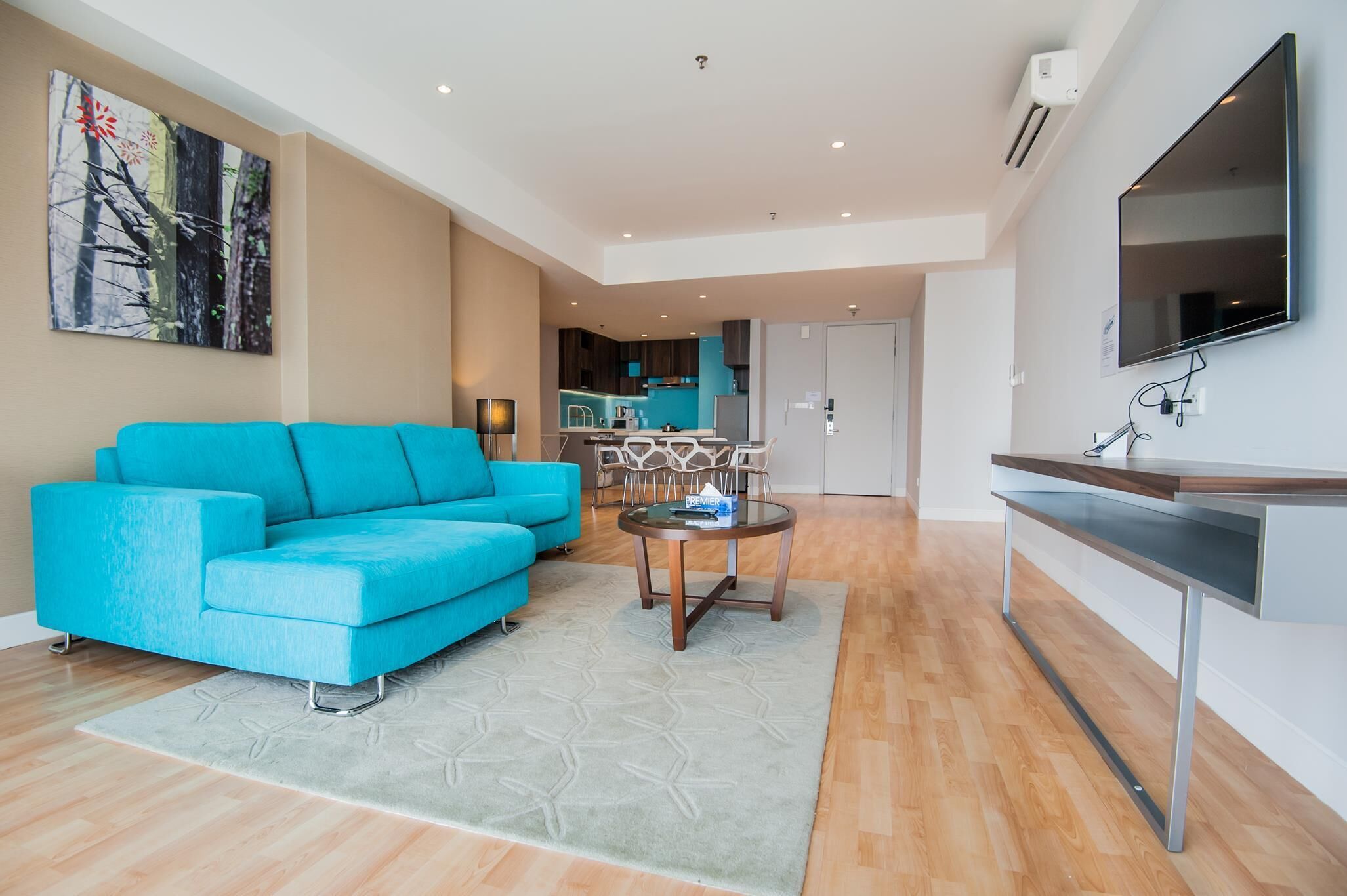 A modern living room with a blue sofa, a coffee table, and a TV mounted on the wall.