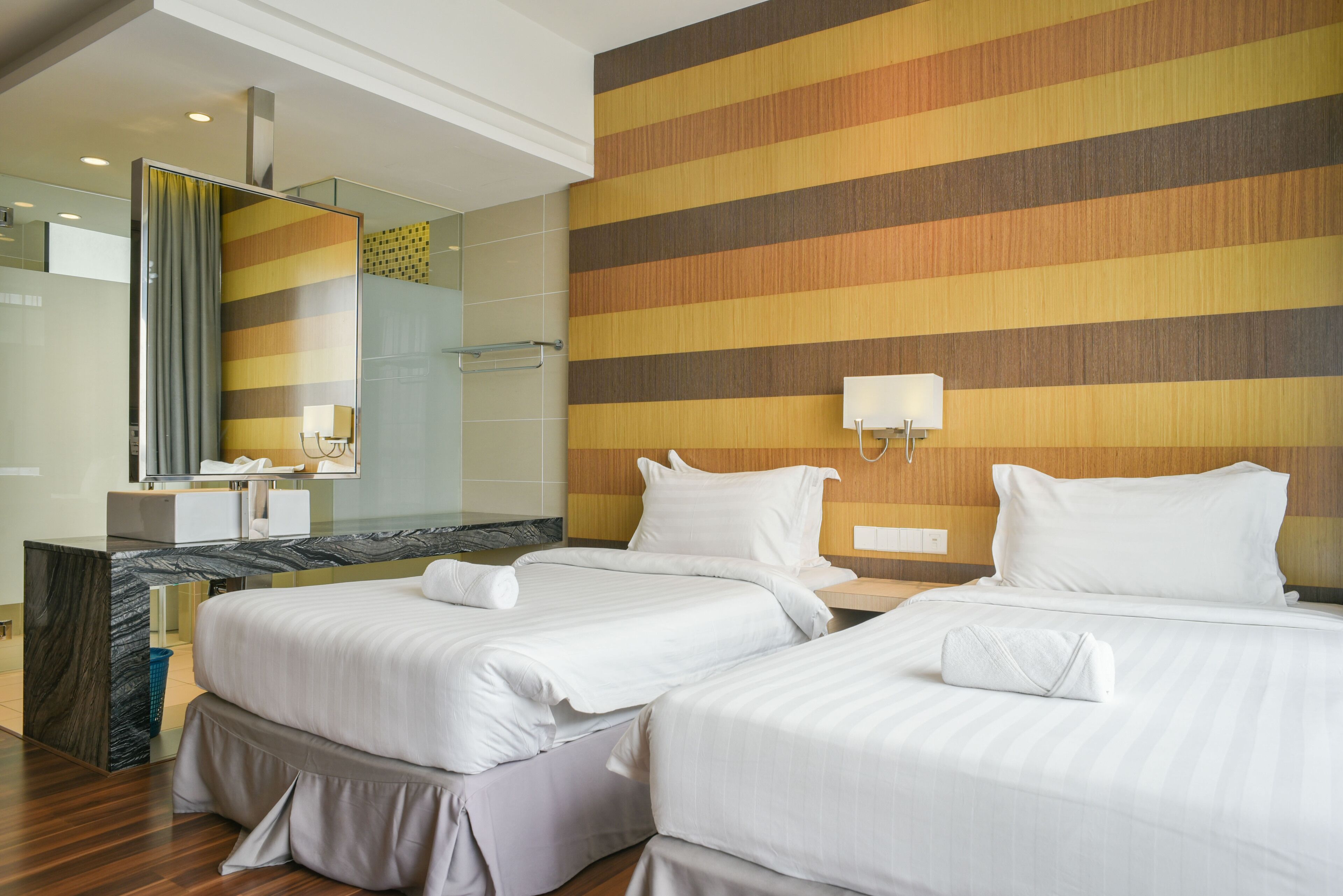 Ein Hotelzimmer mit zwei Betten, einem Badezimmer und einem großen Spiegel.