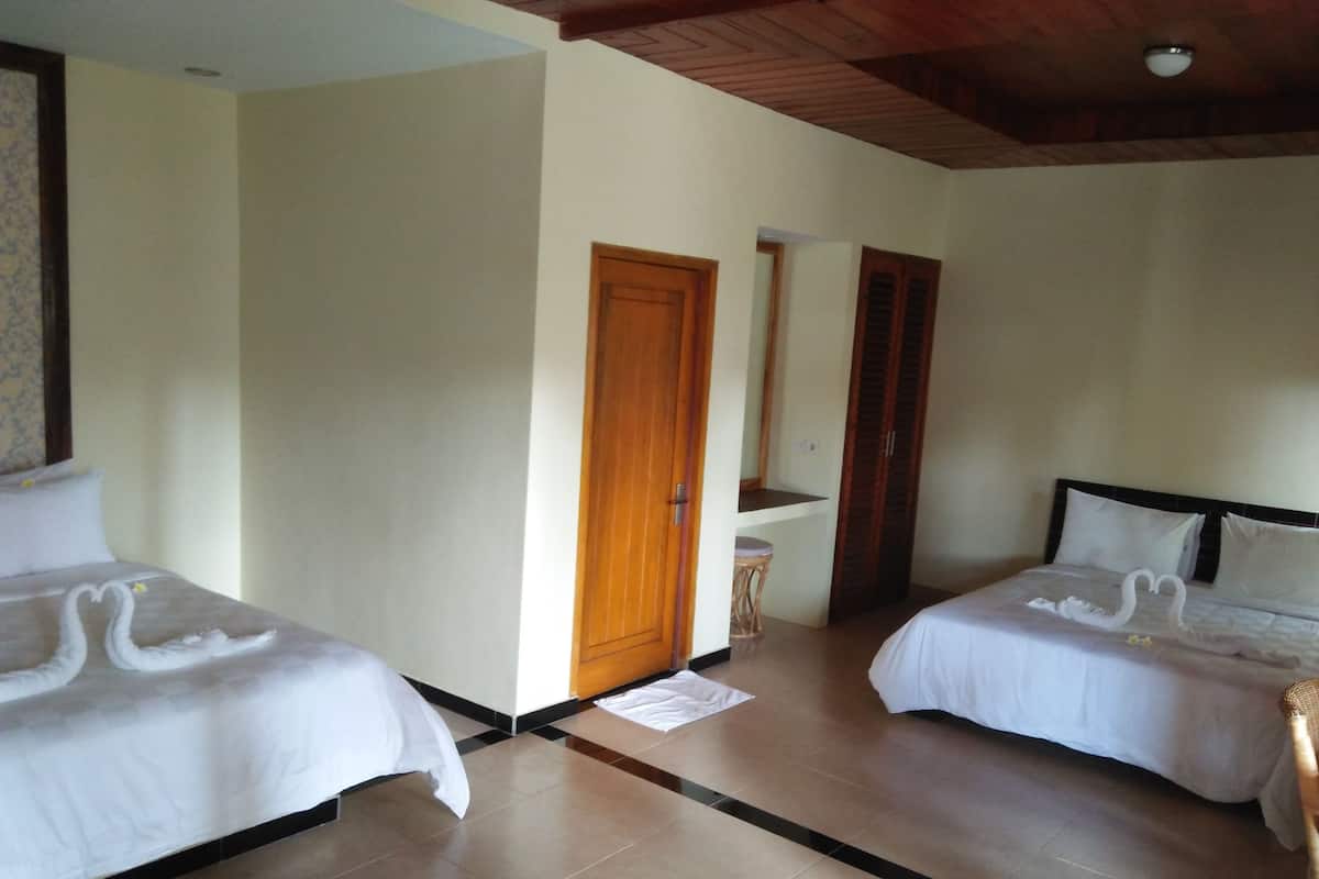 A hotel room with two beds, a wooden door, a small stool, and a mirror on the wall.