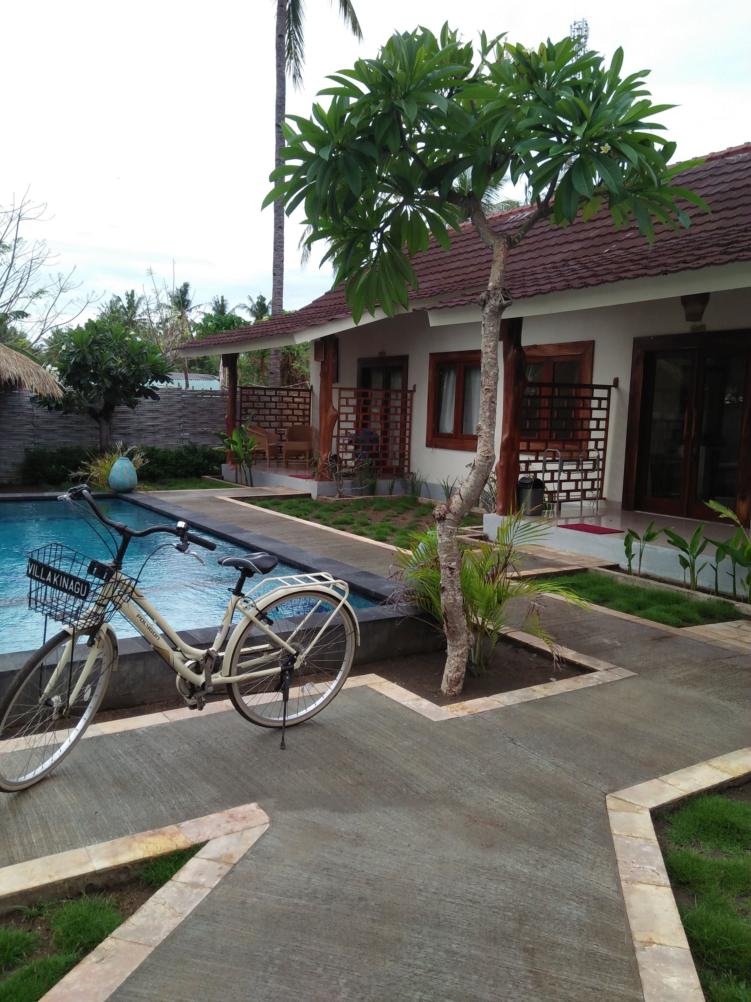 Una casa con piscina, bicicleta y un pequeño árbol.