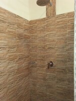 Un área de ducha con pared de textura de piedra y ducha.