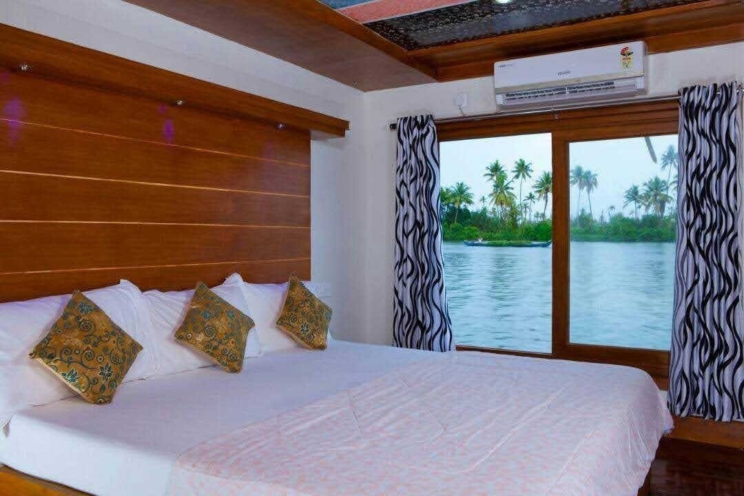 A bedroom with a large bed, wooden headboard, and a view of a body of water through a sliding door.