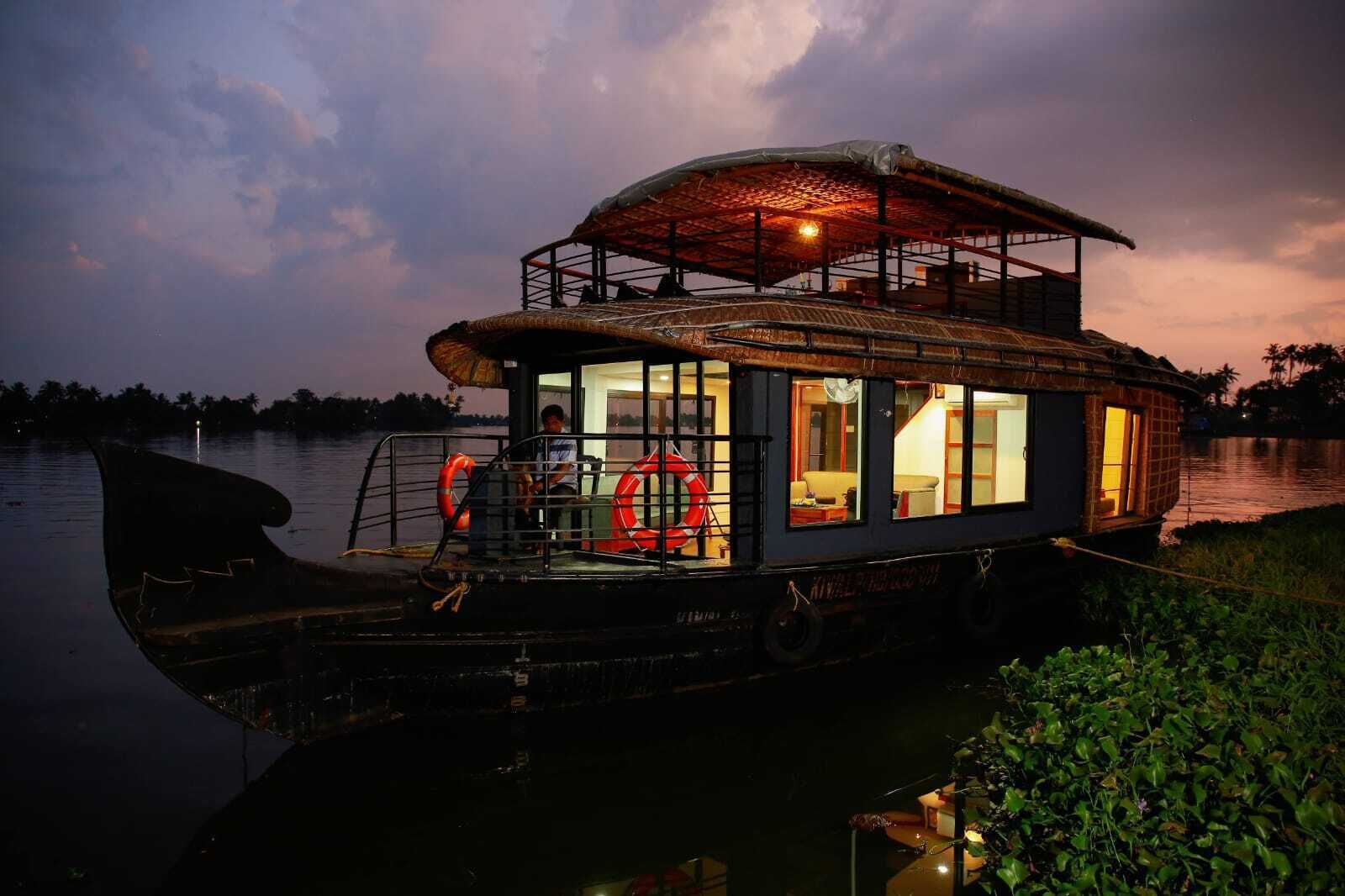 Ein Hausboot mit überdachter Terrasse, Fenstern und einem Rettungsring.