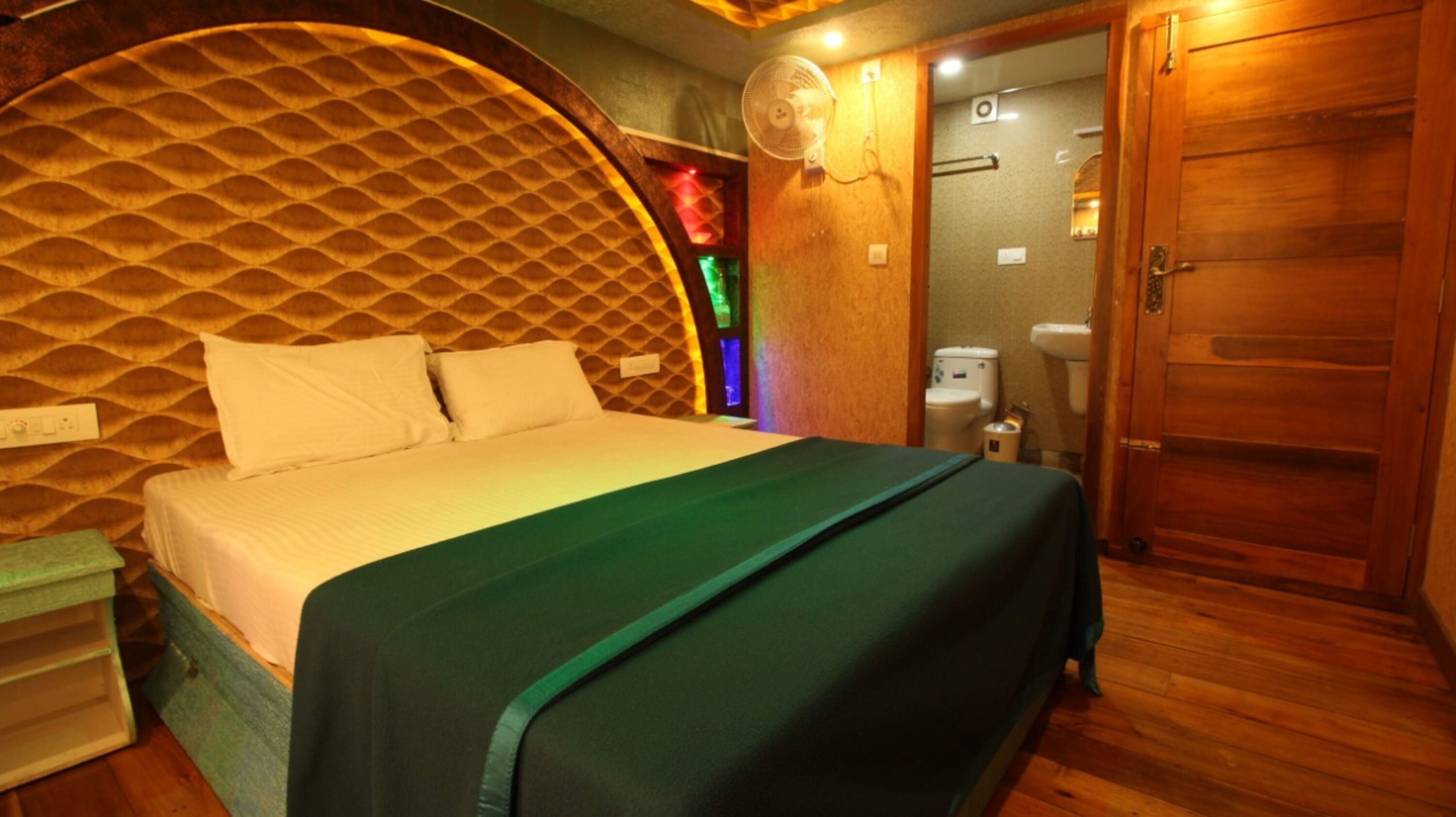 A room with a bed, a wooden door, and a bathroom visible through an open door.