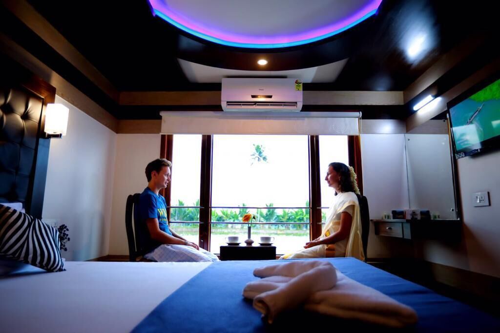 Una habitación con cama, mesa de masajes y un ventanal con vistas a la vegetación.