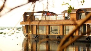 Une péniche dotée d’une terrasse couverte et de fenêtres, flottant sur l’eau.