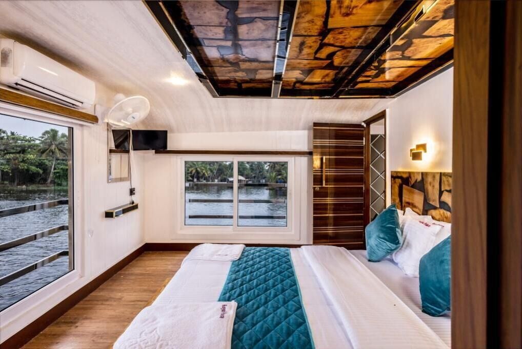 Un dormitorio con una cama grande, una ventana con vistas al agua, un ventilador de techo y un cabecero de madera.
