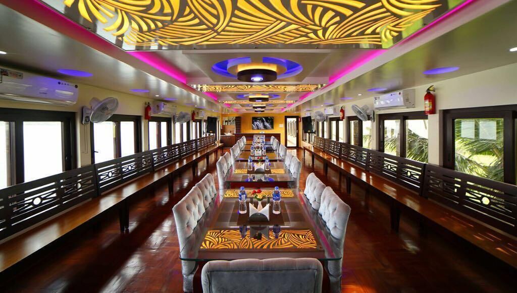 A dining area with a long table, chairs, and a ceiling with decorative lighting.