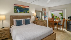 Une chambre comprenant un lit, des tables de chevet, un bureau, des chaises et un coin cuisine.