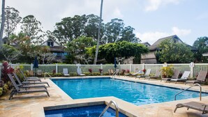 Une piscine avec des chaises longues et une clôture blanche.