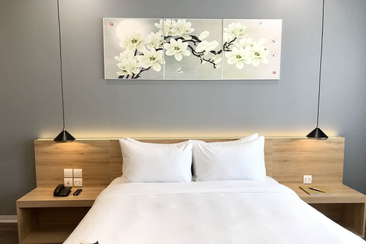 A neatly made bed with white linens, a wooden headboard, and bedside tables with lamps.