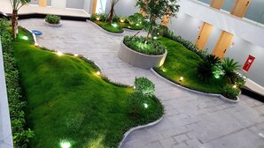 Een moderne binnentuin met strak gemaaid gras, plantenpotten en sfeerverlichting.