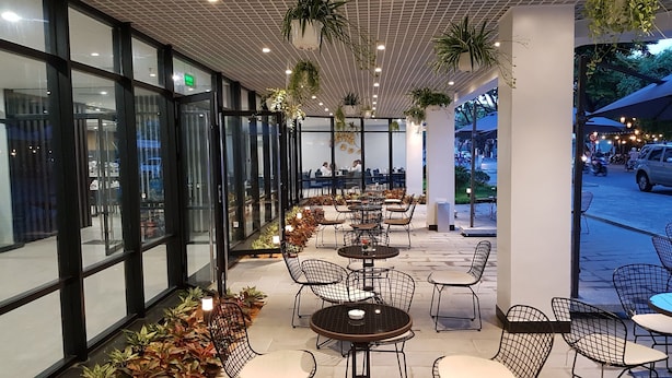 Een terras met tafels en stoelen, plantenbakken en uitzicht op de straat.