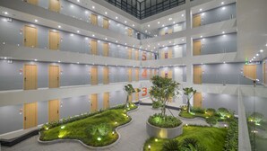Een open hotelatrium met genummerde balkons, een centraal gelegen tuin en een modern architectuurontwerp.