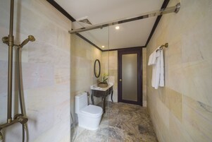 Casa de banho com cabine de duche em vidro, sanita, lavatório com espelho e barra de toalhas.