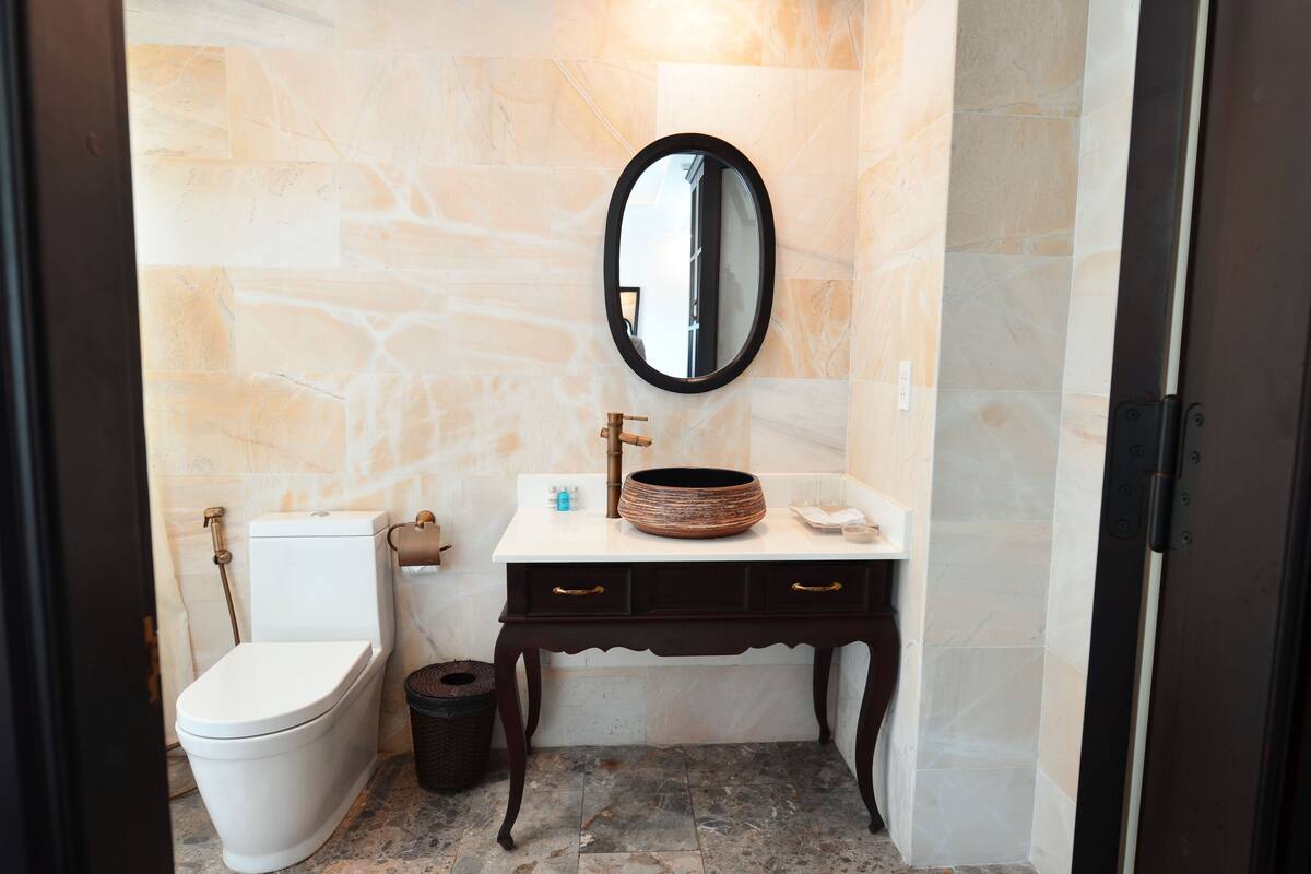 A bathroom with a toilet, sink, and mirror.
