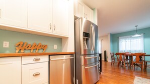 A modern kitchen with white cabinets, a stainless steel refrigerator, and a wooden countertop. - Walking Distance to Shops, Beach, Restaurants and Brewery  (New Buffalo)