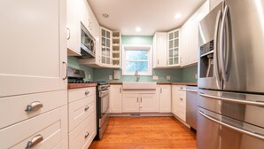 A kitchen with white cabinets, stainless steel appliances, and a wooden floor. - Walking Distance to Shops, Beach, Restaurants and Brewery  (New Buffalo)