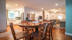 A spacious kitchen with a dining area, wooden chairs, and a large round table. - Walking Distance to Shops, Beach, Restaurants and Brewery  (New Buffalo)