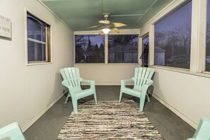 Relax in this serene space with a ceiling fan overhead, two comfortable chairs, and a beautiful view of the outdoors.
