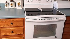 Une cuisine avec un fourneau blanc, des armoires en bois et un four encastré.