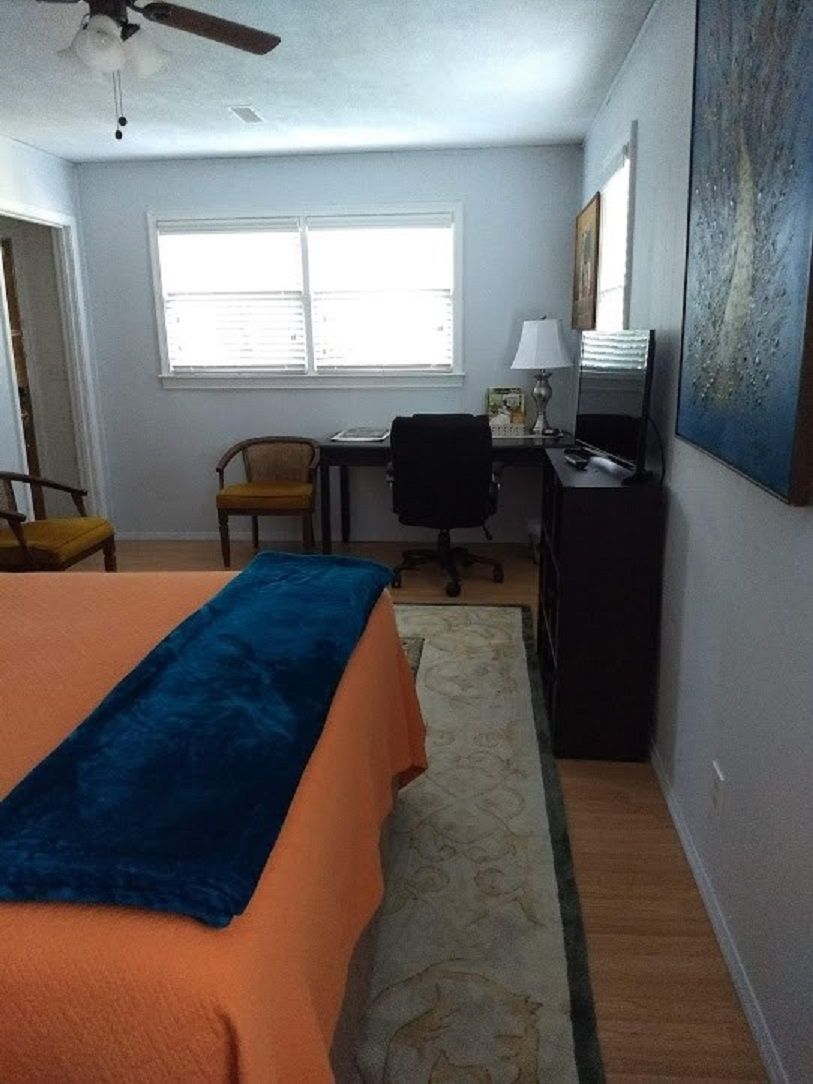 Un dormitorio con cama, escritorio, silla y ventana.