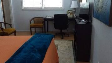 Un dormitorio con cama, escritorio, silla y ventana.