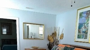 Une chambre à coucher avec un lit, une table de chevet, un miroir et un tableau encadré au mur.