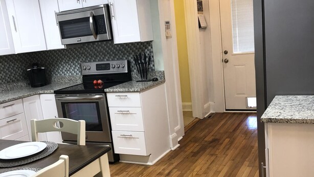 A compact kitchen with white cabinets, a microwave, a stove, and a refrigerator. - 1 Block to the Beach, Fully Fenced in Backyard, Golf Cart Included (Myrtle Beach)