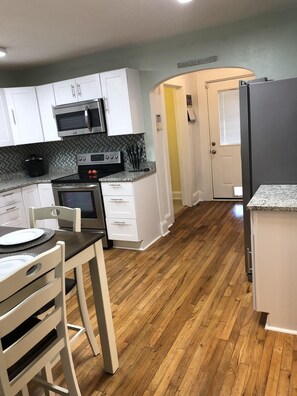 A compact kitchen with white cabinets, a microwave, a stove, and a refrigerator.