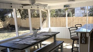 An outdoor patio with a wooden table set for dining, a bar area, and a covered seating space. - 1 Block to the Beach, Fully Fenced in Backyard, Golf Cart Included (Myrtle Beach)