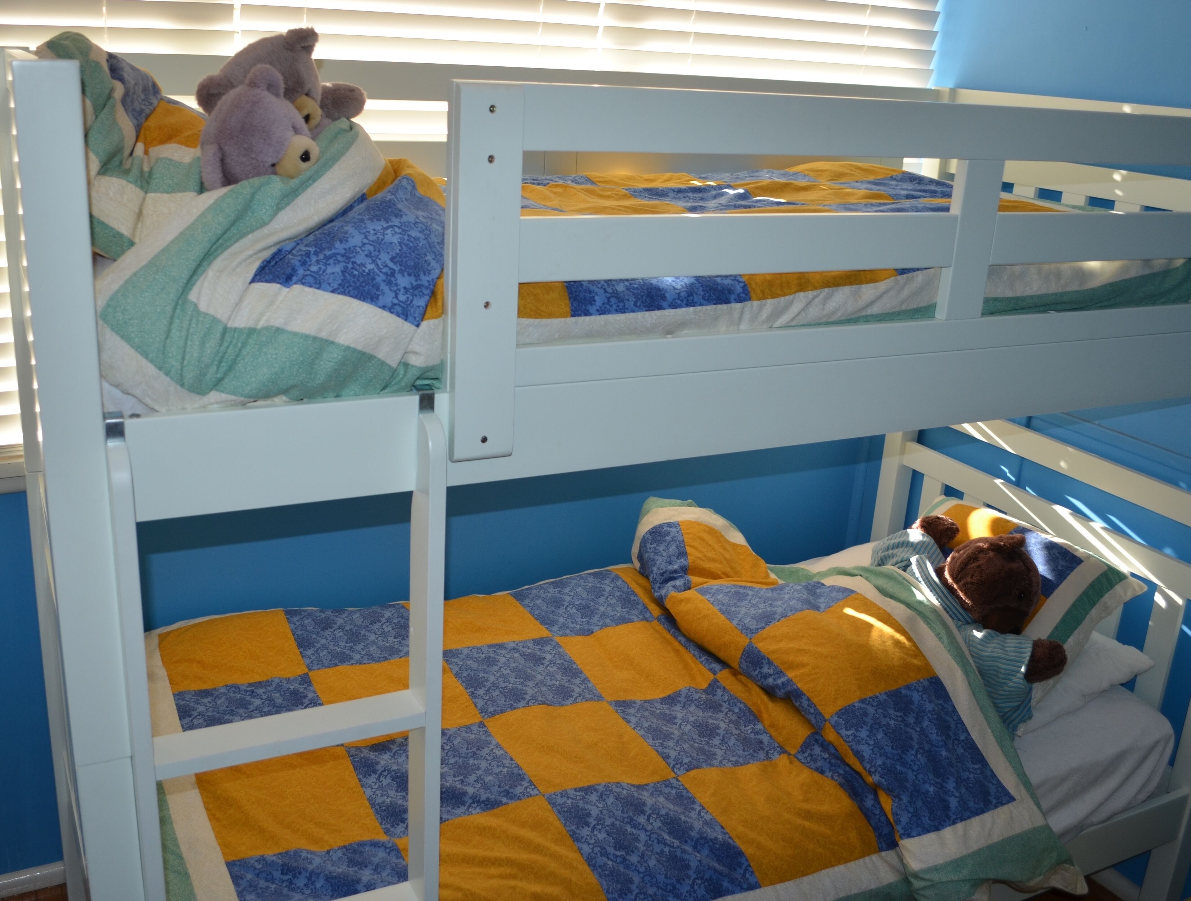 Un lit superposé avec une couverture à carreaux et des peluches.