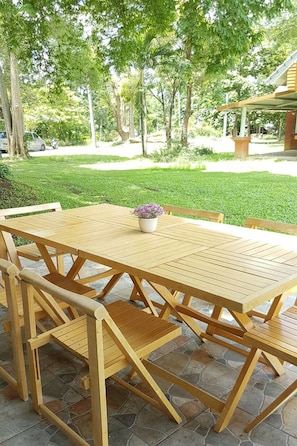 Een houten tuintafel met stoelen op een stenen terras, inclusief een potplant.