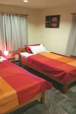 Een kamer met twee eenpersoonsbedden, een nachtkastje met een lamp en een schilderij aan de muur.