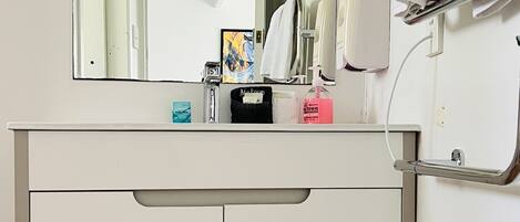 A bathroom with a white vanity, a large mirror, and a towel rack.
