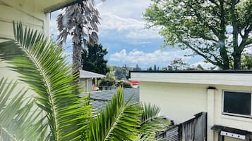 A residential area with a white building, a wooden fence, and a large tree.
