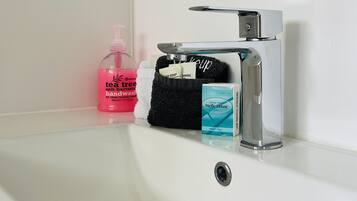 A bathroom sink with a mirror above it, a black towel, a soap dispenser, a facial tissue box, and a bottle of hand soap.