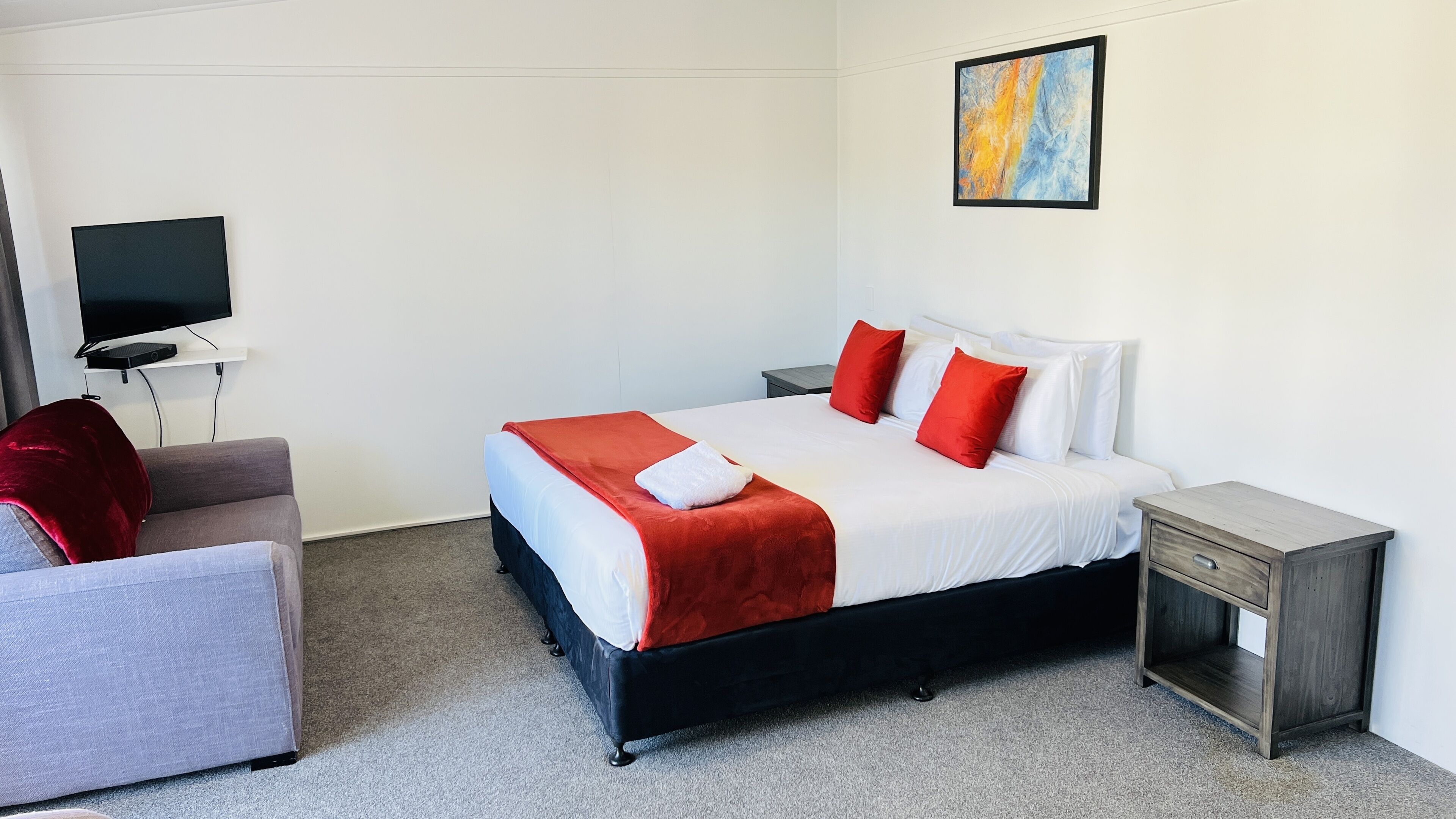 A hotel room with a bed, a TV, a desk, and a chair.