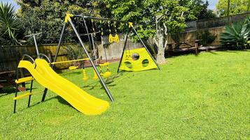 Un parque infantil con un tobogán amarillo y columpios.