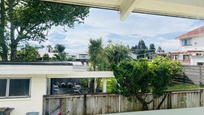 Zona residencial con valla de madera, un patio con mobiliario exterior y vistas a casas y árboles vecinos.