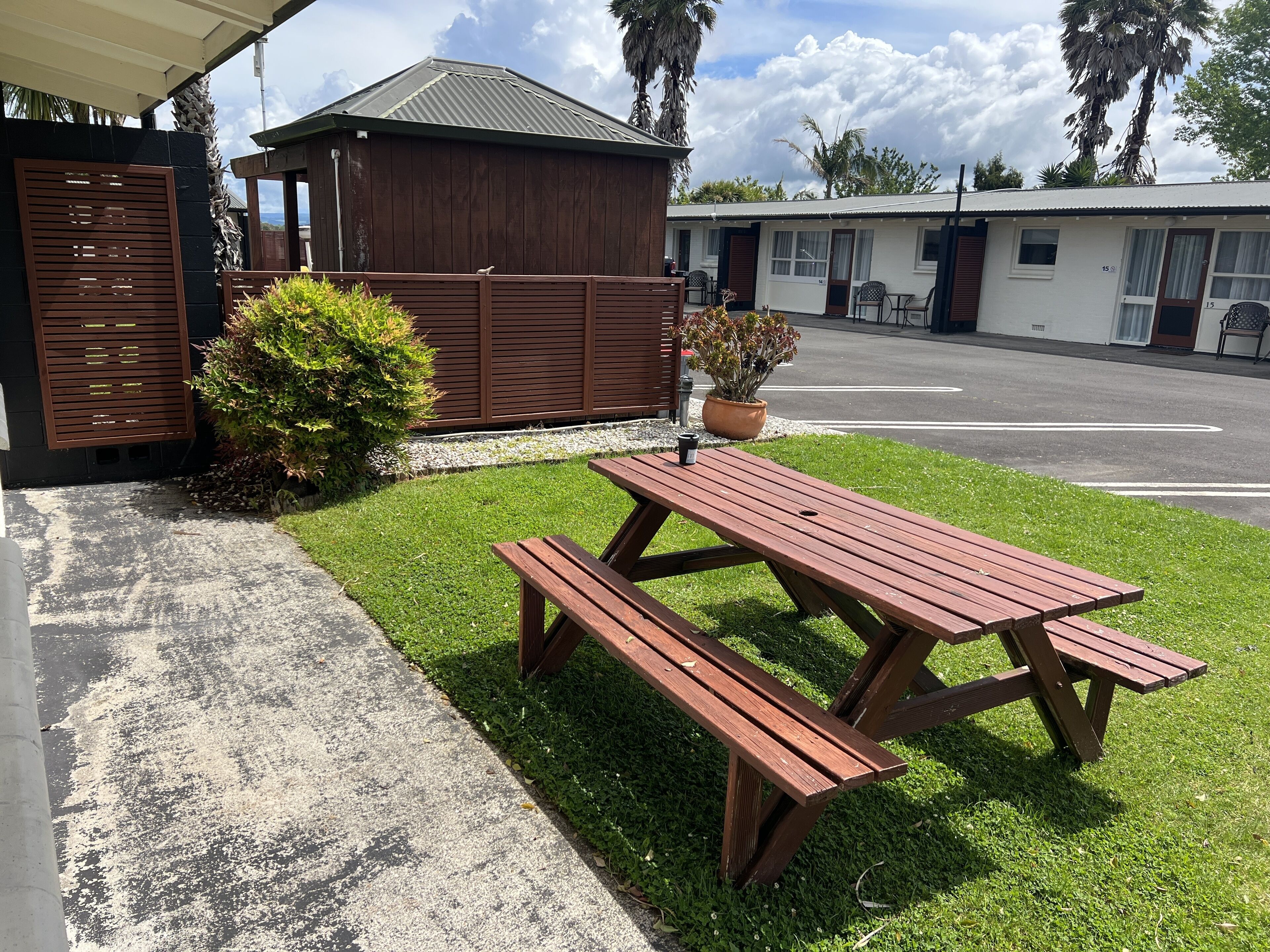 A picnic table with benches, a small wooden structure, and a potted plant.
