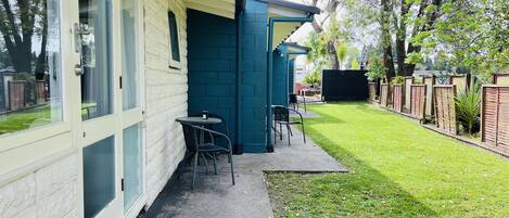 Ein Gebäude mit einer Terrasse, Sitzgelegenheiten im Freien und einem gepflegten Rasen.