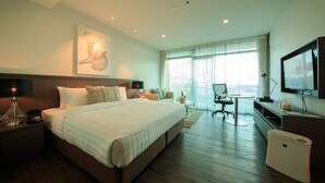 A hotel room with a large bed, bedside table, lamp, and a TV on the wall.